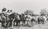 Group of unidentified Sioux Indians wearing headdresses while on horseback in field 1910.png